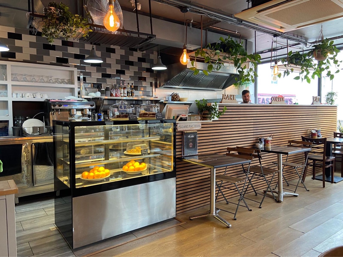 Caffè Aldo's counter with cake cabinet, fresh oranges and wood-slat wall